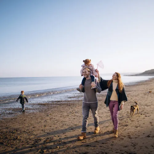 Three generation family enjoying walking along the coast. Its cold outside so they are wrapped up warm.
